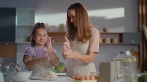 Smiling Woman and Girl Shaking Off Flour From Hands on Kitchen. Portrait