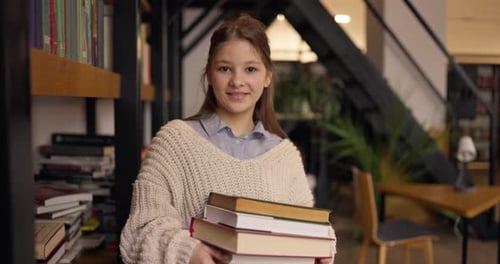Smiling Teen Girl Holding Books in a Library