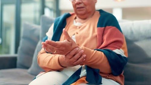 Senior Woman Massaging Her Wrist in Home Setting