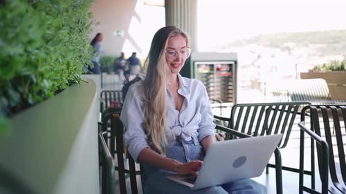 Freelancer mit Laptop sitzt auf der Café-Terrasse im Freien