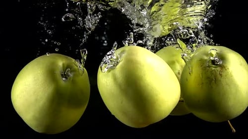 Slow Motion Yellow Apple Falling Underwater on Black Background
