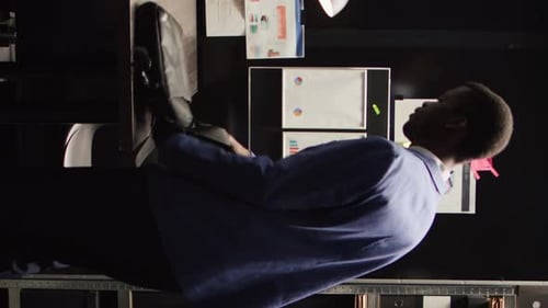 Man Analyzes Graphics at Desk in Dark Office