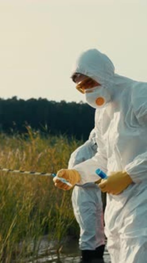 Scientists in protective suits take samples outdoors