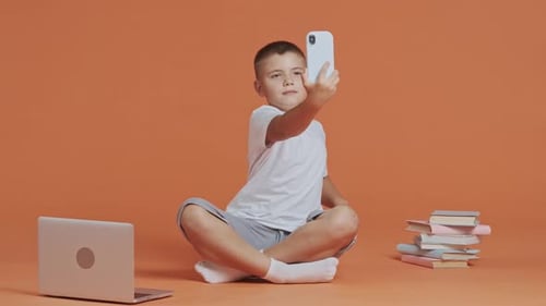 Boy Taking Selfie With Phone on Studio Background
