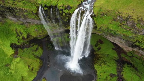 Top-Down Aerial View of River Flowing to Small Waterfall on Green Cliff.