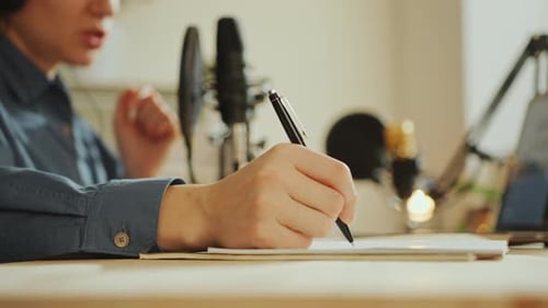 Female Podcaster Taking Notes and Speaking in Mic at Recording Studio