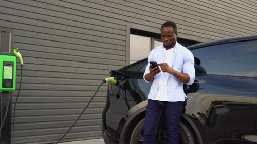 African American Man Charging Electric Car at Station