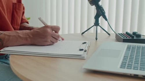 Tattooed Person Works at Desk with Microphone