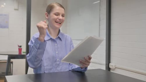Young Woman Excitedly Reviews Documents in Modern Office