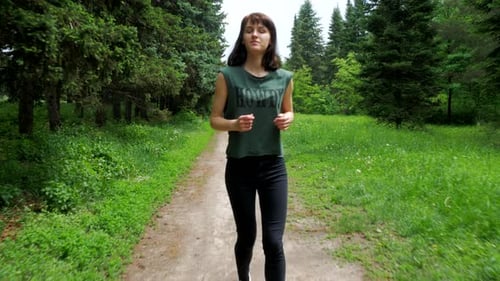 Slim athletic girl does morning running in the summer park