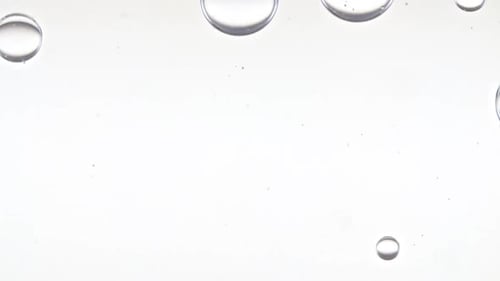 Bolhas transparentes se formam e flutuam para outras em uma superfície transparente sobre fundo branco O medicamento