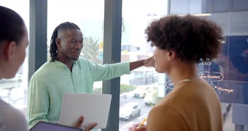 Discutindo o projeto, colegas usando laptop e quadro branco em uma reunião de escritório moderna
