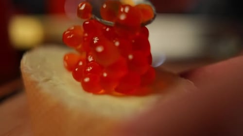 Adding Delicious Red Caviar to Bread with Spoon