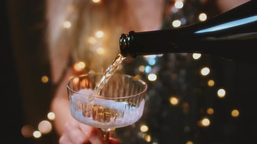 Mãos femininas seguram copos redondos para mulheres com champanhe em um vestido cintilante