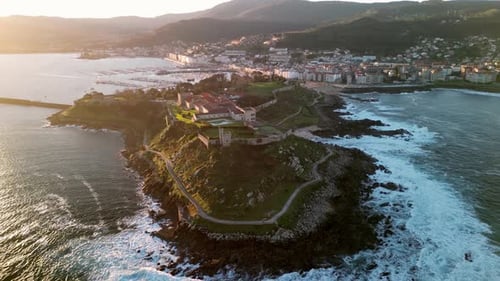 Aerial view of medieval fort overlooking coastline at sunset, Spain.