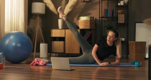 Woman Doing Leg Lifts While Watching Laptop