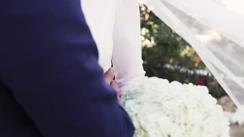 Slow motion close up of the bride and groom kissing at the wedding with bouquet of flowers in hand