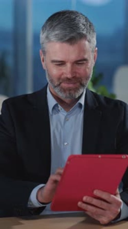 Professional Man Engrossed in Using a Tablet While Working in a Modern Office Setting