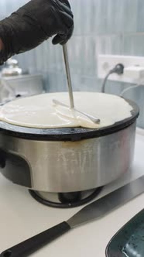 Le chef étale la pâte à crêpes sur une plaque chauffante