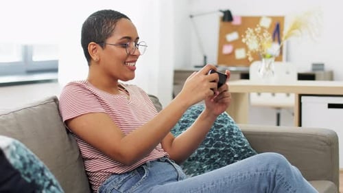Smiling woman sitting and playing game on smartphone