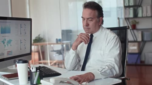 Älter Unternehmer, der mithilfe des Computers über einen Geschäftsplan nachdenkt