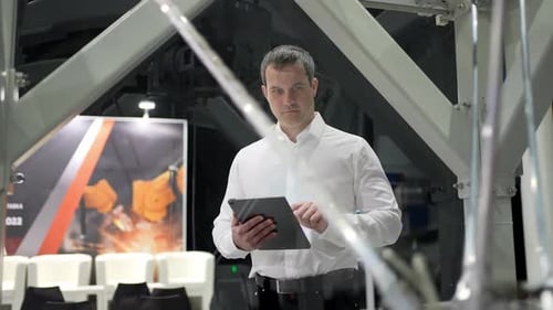 Engineer Man Using Tablet at Industrial Robot Robotic Arm Technology in Manufacturing and
