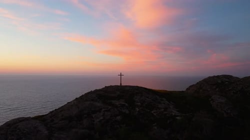 Silhouette of Hilltop Cross Against Vibrant Sunrise Sky