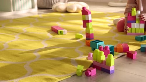 Little girl playing with toys on floor in playroom. Camera moving