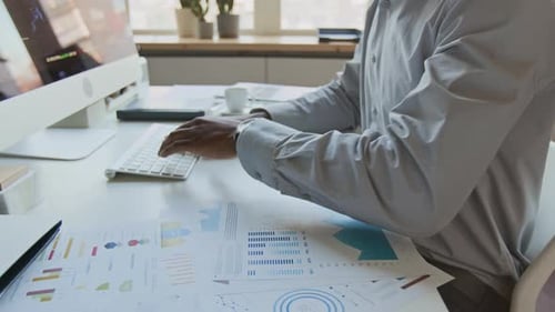 Anonymer schwarzer Geschäftsmann arbeitet am Computer mit Finanzdiagrammen
