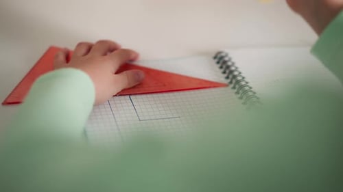 Grundschüler zeichnet am Schreibtisch eine quadratische Seite