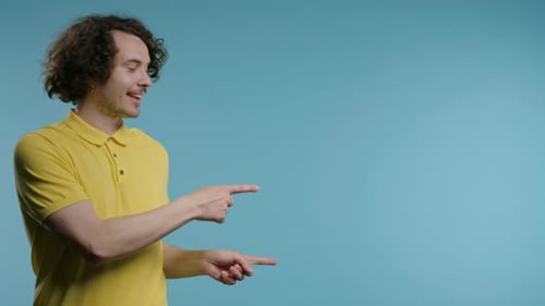 Young Man Points to the Right on Blue Background