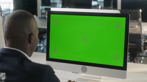 Business AfricanAmerican Man Working on Desktop Computer with Green Screen Mock Up Display in Busy