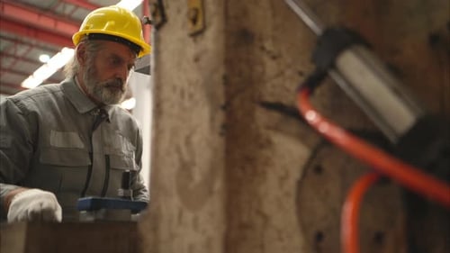 Senior experienced technician checking and maintenance a large machine in metal sheet factory