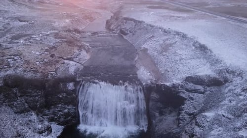 Aerial top shot of Borufoss waterfall in Iceland during a winter sunrise moving backward
