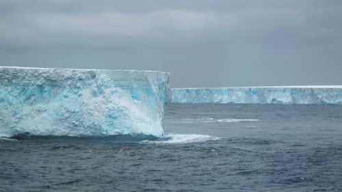 Two huge tabular icebergs on a cloudy day.