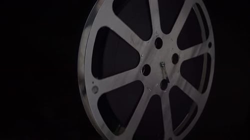 Metal Film Reel Spinning on Dark Background