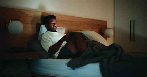 Man Relaxing in Bed Using a Tablet