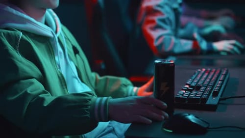 Young Chinese Man with Energy Drink Playing Game at Cyberclub