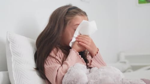 Sick Child Wipes Nose with Tissue in Bed