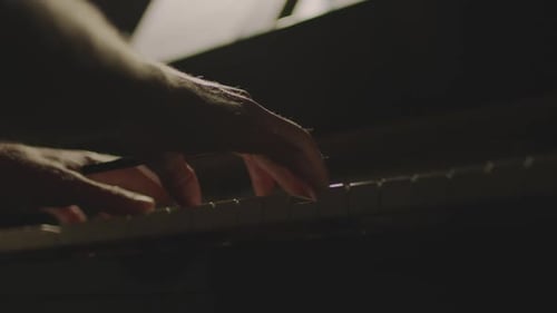 Hands Playing Piano in Dim Light