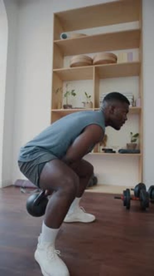 Strong Man Performing Alternating Kettlebell Swings in Home Gym