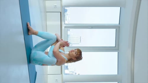 Écran vertical : femme pratiquant la pose de Half Lord Of The Fishes dans un studio de yoga