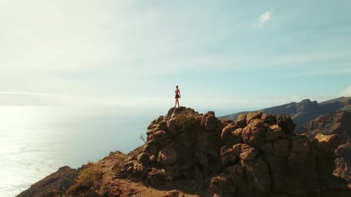 Solo traveler observes the Atlantic from a high vantage point on Tenerife rugged cliffs. Peacefulnes