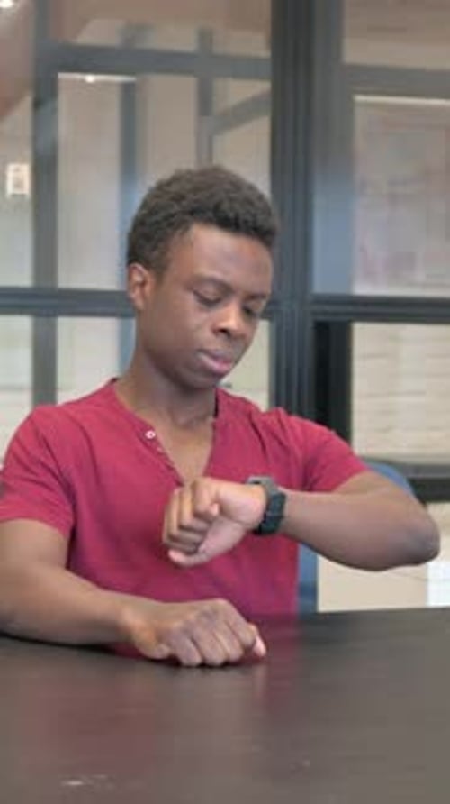 Young Adult Looking at Watch in Office Setting