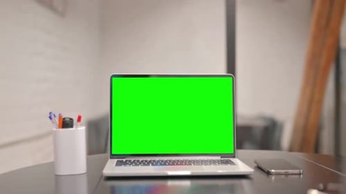 Laptop with Green Screen on Desk in Office
