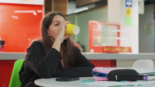 Teen Girl Drinks from Cup While at School