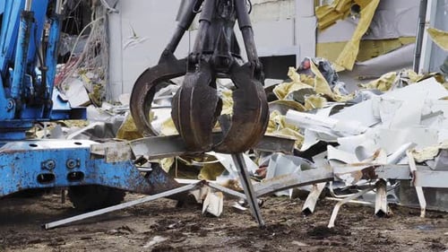 Une excavatrice démonte les décombres sur le site de démolition d'un stade