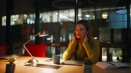 Woman Contemplates at Desk in Office at Night