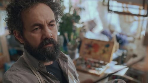 Focused Artist Painting on Canvas with Brush in Creative Workshop