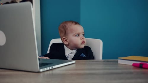 Adorable Infant Sits at Desk with Laptop